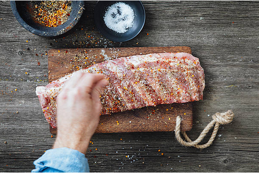 Cuisinier qui prépare des ribs de porc avant de les faire cuire